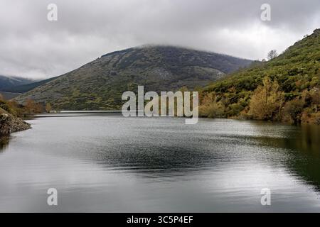Calmo bacino idrico che riflette montagne e alberi in un paesaggio panoramico di Palencia, Spagna. Foto Stock