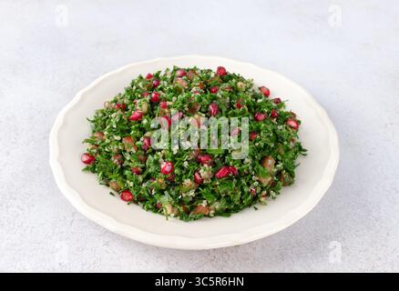 Insalata levantina vegetariana con quinoa, pomodori, melograno, prezzemolo, limone e condimento Foto Stock