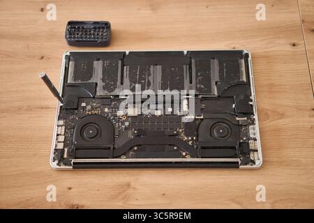 Computer portatile smontato insieme a vari utensili posizionati ordinatamente su una superficie in legno per le riparazioni Foto Stock