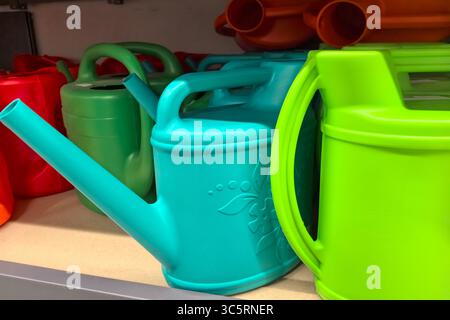 Le lattine colorate si trovano ordinatamente sullo scaffale del negozio, mostrando varie sfumature di blu, verde e rosso. Attendono le mani degli amanti del giardinaggio Foto Stock