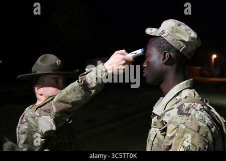 31 marzo 2020 - Fort Jackson, Carolina del Sud, Stati Uniti - il sergente Joshua Cruz, un sergente d'addestramento assegnato alla compagnia A, 2nd Battalion, 13th Infantry Regiment, prende la temperatura di Pvt. Prince Aning, un guardiano dell'Ohio, prima di salire a bordo di un autobus il 31 marzo 2020. Aning, insieme a circa 400 altri laureati del Basic Combat Training, furono trattenuti a Fort Jackson, Carolina del Sud, dopo la laurea a causa del virus COVID-19. Ogni temperatura dei soldati è stata registrata prima di salire a bordo degli autobus per Fort Lee, Virginia, dove parteciperanno all'Advanced Individual Training. (Immagine di credito: © Alexand Foto Stock