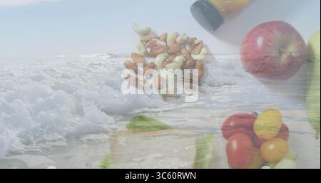 Le noci riposano sulla sabbia della spiaggia, con barattolo di salsa gialla con pomodori ciliegini verdi di mela rossa Foto Stock