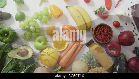 Esposizione di frutta e verdura fresca sul piano di lavoro della cucina, con vaso in vetro di succo e grattugia in metallo Foto Stock