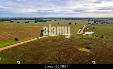 Splendida vista aerea dell'ampio paesaggio di Casanare, Colombia, con campi ondulati e una tortuosa strada sterrata. Foto Stock