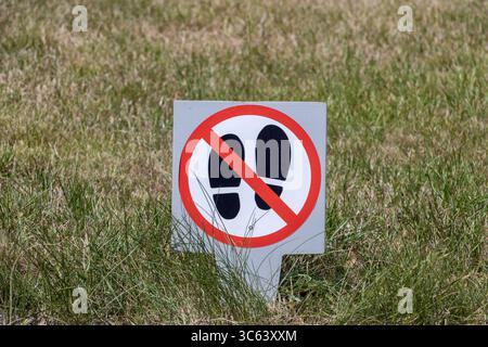 Cartello indicante il divieto di camminare sull'erba in un'area verde pubblica Foto Stock