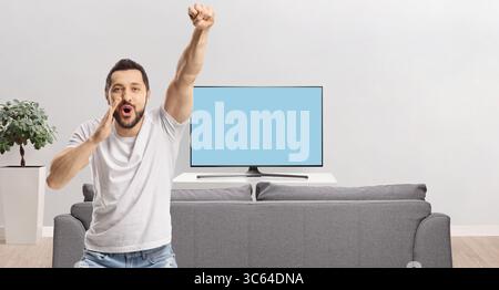 Un giovane tifo e grida davanti a uno schermo tv a casa Foto Stock