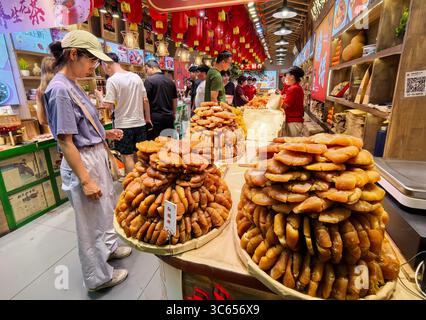 Pechino, Cina. 30 luglio 2025. Le persone selezionano spuntini in un negozio in Gulou Street a Pechino, capitale della Cina, 30 luglio 2025. Pechino ha sviluppato vigorosamente la sua economia notturna dall'inizio di quest'estate, con cucina locale, film all'aperto, festival musicali e mercati notturni. Crediti: Li Xin/Xinhua/Alamy Live News Foto Stock