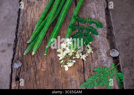 Cialde di bacchette di bacchette di verdure e foglie sane. Moringa Oleifera con foglie su fondo in legno Foto Stock