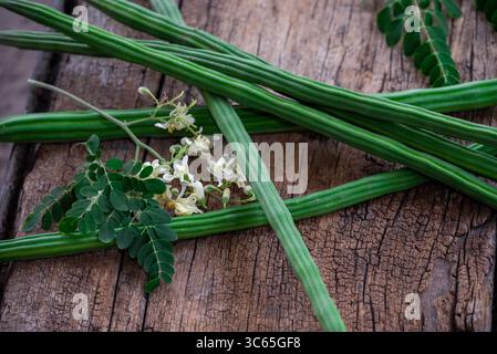 Cialde di bacchette di bacchette di verdure e foglie sane. Moringa Oleifera con foglie su fondo in legno Foto Stock