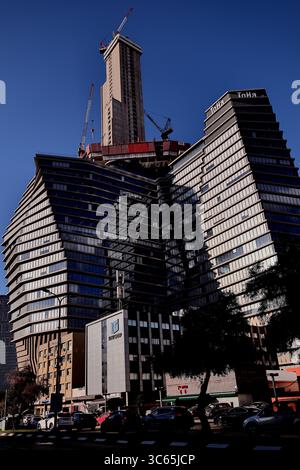 L'imponente costruzione della ToHa Tower 2 a Tel Aviv-Jaffa mette in mostra scintillanti curve di vetro e gru contro un vivace skyline, celebrando l'evoluzione urbana Foto Stock