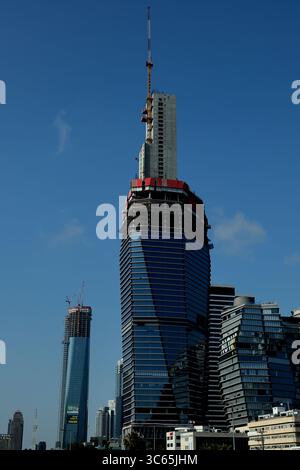 Le gru da costruzione incoronano una torre ToHa 2 a Tel Aviv-Jaffa, mentre le facciate in vetro rispecchiano il sole che mostra la crescita dinamica dell'architettura urbana. Foto Stock
