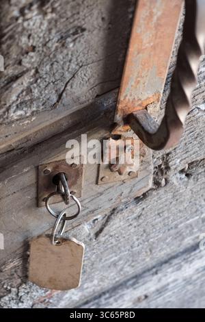 Vecchia porta in legno intemprata con vernice sbucciante e texture vintage, adagiata in un rustico muro di pietra. Un dettaglio pieno di storia, colore e carattere antico. Foto Stock