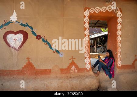 Chapai Nawabganj, Bangladesh - 14 giugno 2019: Veduta di una giovane donna in una porta, incorniciata da arte geometrica e floreale tradizionale su un muro di argilla. Foto Stock