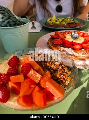Brunch colorato con frutta fresca, muesli e waffle serviti all'aperto Foto Stock