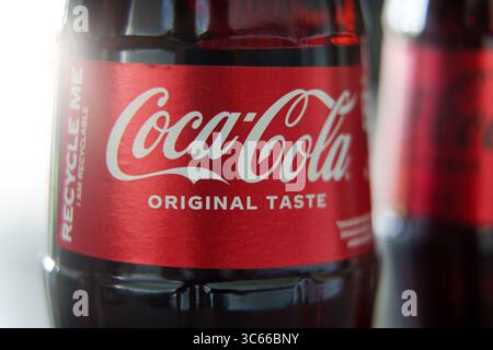 Primo piano di una bottiglia di Coca-Cola in vetro che mostra l'etichetta rossa originale con condensa e messaggio riciclabile Foto Stock
