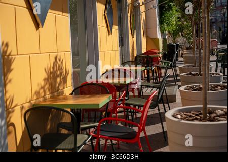 Street Cafe con mobili rossi, gialli e verdi luminosi e piante in grandi vasi Foto Stock