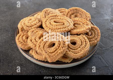 Spuntino indiano fritto murukku o chakali su un fondale scuro. Cibo tradizionale Diwali. Cucina indiana Foto Stock