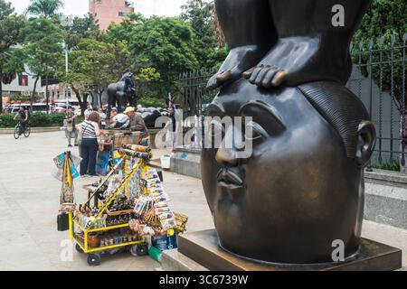 Carrello souvenir collocato accanto alla scultura di Botero chiamata "pensiero" in Plaza Botero a Medellin, Colombia. Foto Stock