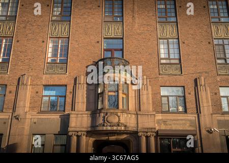 Facciata in stile Art Deco di uno storico edificio finlandese a Vyborg, nell'Oblast' di Leningrado: Muratura illuminata dal sole, finestre a bovindo e un balcone ornato. Foto Stock