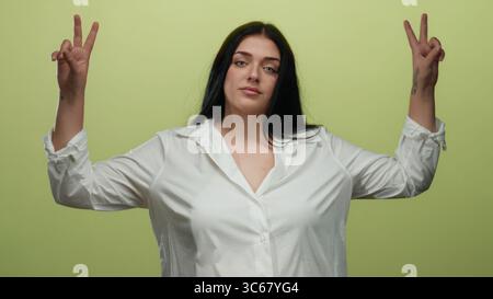 Giovane donna che gestiva con sicurezza davanti a sfondo giallo isolato, sottolineando la moda curvata e le dimensioni e la positività corporea in un ambiente informale. Foto Stock