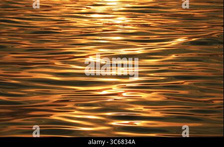 Magnifiche riflessioni dorate dell'alba sulla superficie del mare Foto Stock