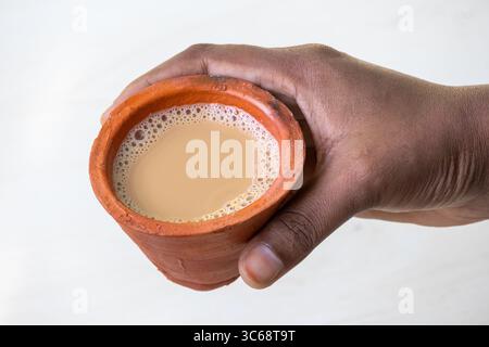 La mano di una donna regge una tazza di masala caldo chai o Kadak Chai in una tradizionale tazza di argilla. Foto Stock