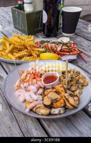 Piatto di pesce a Osbournes, Leigh-on-Sea, Essex, Regno Unito: Aragosta, gamberi, cozze, patatine fritte e spicchi di limone serviti durante il pranzo estivo. Foto Stock