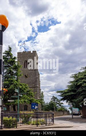 Chiesa storica a Leigh-on-Sea, Essex, Inghilterra, con il mare visibile sullo sfondo sotto un cielo nuvoloso, incorniciato da alberi e cartelli stradali. Foto Stock