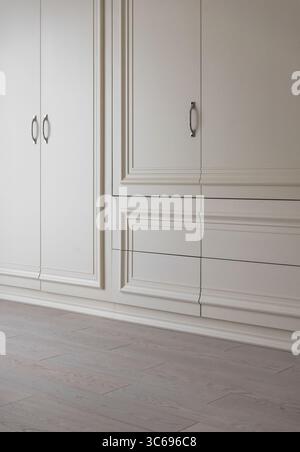 Porte bianche in camera. Esterno classico dell'armadio bianco crema con manici verticali. Foto Stock