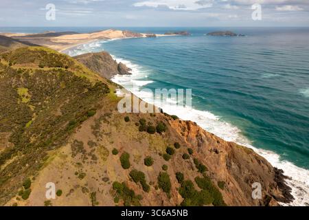 Vista aerea di una costa frastagliata con un faro arroccato su una scogliera che si affaccia sull'oceano e sulle dune sabbiose in lontananza, Whangarei, Northland Region, nuova Zelanda. Foto Stock