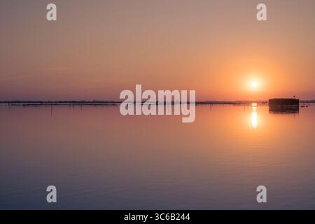 Un classico scatto al tramonto sulla laguna di Porto Caleri, in provincia di Rovigo, Veneto, Italia. Parte del Parco regionale del Delta del po. Foto Stock