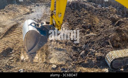 Immagine ravvicinata di una pala da braccio che lavora in cantiere per lo spostamento di terra e terra. Movimento terra, scavi, scavo su terreni Foto Stock