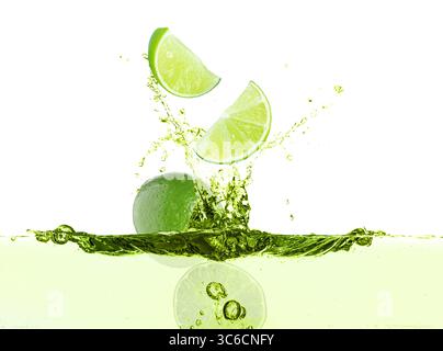 Limes freschi che cadono in una bevanda da spruzzo su sfondo bianco Foto Stock