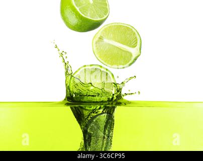 Limes freschi che cadono in una bevanda da spruzzo su sfondo bianco Foto Stock