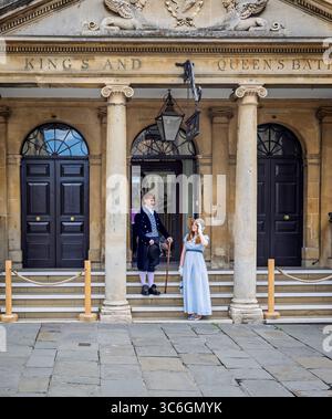 Coppia di giovani vestiti con costumi del periodo Jane Austen all'ingresso delle terme romane di Stall Street, Bath, Somerset, Regno Unito, il 31 luglio 2025 Foto Stock