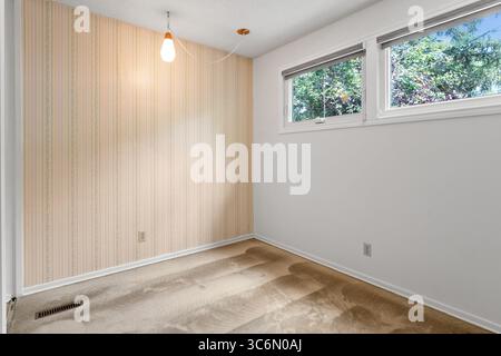 Camera piccola con un muro bianco e una carta da parati a righe. La camera è vuota e ha un aspetto pulito e minimalista Foto Stock