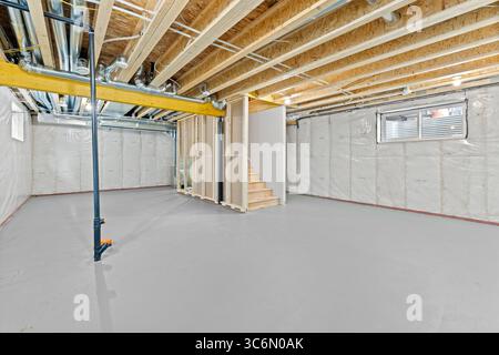 Grande camera vuota con una scala al centro. La camera è incompiuta e ha molte potenzialità Foto Stock