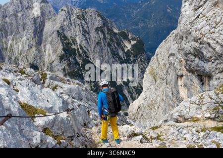 Alpinista sul sentiero di montagna delle Alpi. Uomini che indossano casco e imbracatura che arrampicano in ferrata sulla cima del monte Zugspitze in Germania in estate Foto Stock