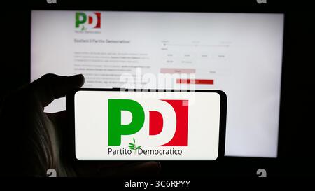 In questa foto, una persona ha in mano un cellulare con il logo del Partito Democratico (PD) sullo schermo davanti alla pagina web. Foto Stock