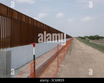 Una vista dettagliata del muro di confine tra Stati Uniti e Messico che mostra la struttura e il terreno della recinzione metallica, illustrando l'infrastruttura di sicurezza delle frontiere. Foto Stock
