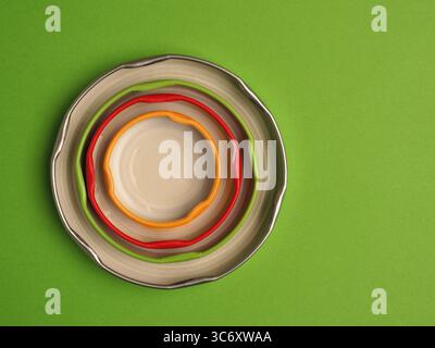 Coperchi colorati in tinta impilati su uno sfondo verde con spazio di testo, vista dall'alto, concetto di riciclaggio Foto Stock