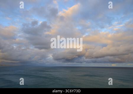 Vista del mare sotto un cielo con colori pastello tenui al tramonto, estate, faro di Nugget Point, Ahuriri Flat, Otago, isola del Sud, nuova Zelanda Foto Stock