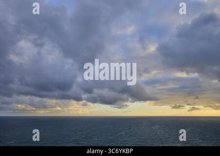 Cielo nuvoloso su un mare calmo, ampio al tramonto, estate, Faro di Nugget Point, Ahuriri Flat, Otago, isola del Sud, nuova Zelanda Foto Stock