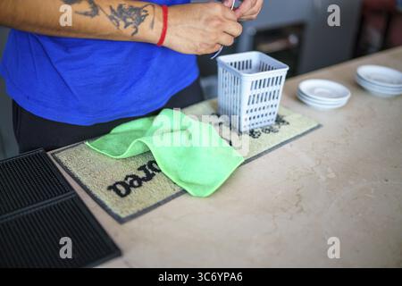 Mani con un panno verde su un tappeto da bar in un ambiente informale, Cremona, Italia 25 luglio 2025 Foto Stock