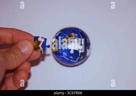 Un globo che rappresenta la Terra poggia su una superficie di puzzle, simboleggiando la connessione globale e la risoluzione dei problemi. Foto Stock
