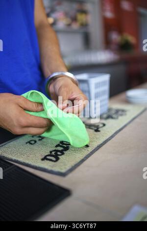 Pulizia delle mani di una superficie con un panno verde su un tappetino da bar, Cremona, Italia 25 luglio 2025 Foto Stock