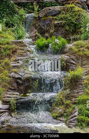 Cascata a più livelli che scende su rocce muschiose Foto Stock
