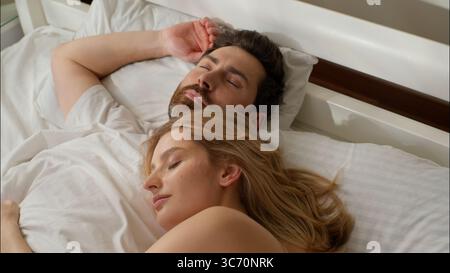 Rilassato partner caucasici femmina maschio dormire coniugato famiglia sdraiato in letto confortevole donna ragazza coccole uomo pigro riposo mattutino in camera amore Foto Stock