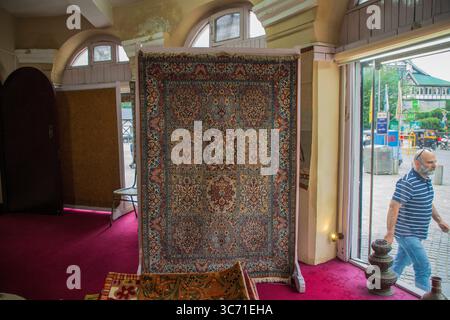 Srinagar, India. 1 agosto 2025. Un uomo passa davanti a un tappeto Kashmiri fatto a mano esposto all'interno di uno showroom nella capitale estiva. Credito: SOPA Images Limited/Alamy Live News Foto Stock