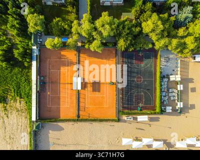 Vista aerea dall'alto dei campi da tennis e da basket di un resort vicino ad una spiaggia sabbiosa Foto Stock